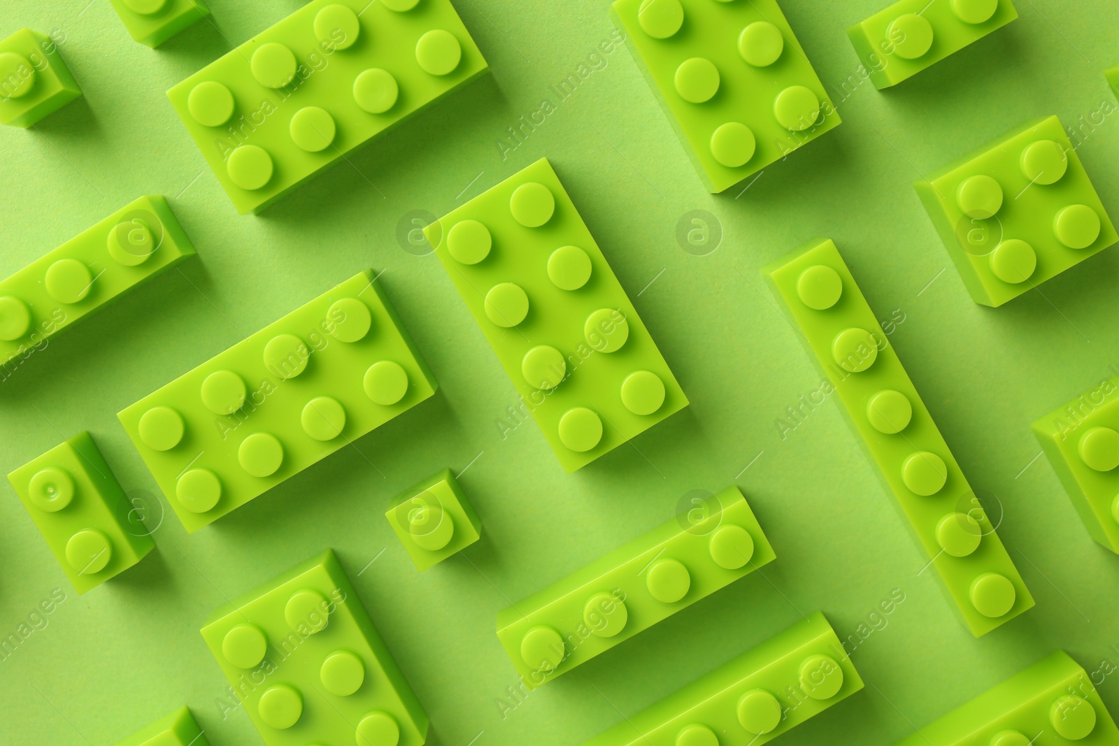 Photo of Constructor toy. Many building blocks on light green background, flat lay