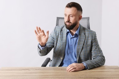 Photo of Man showing something at wooden desk in office, space for text