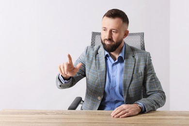 Man pointing at something at wooden desk in office, space for text