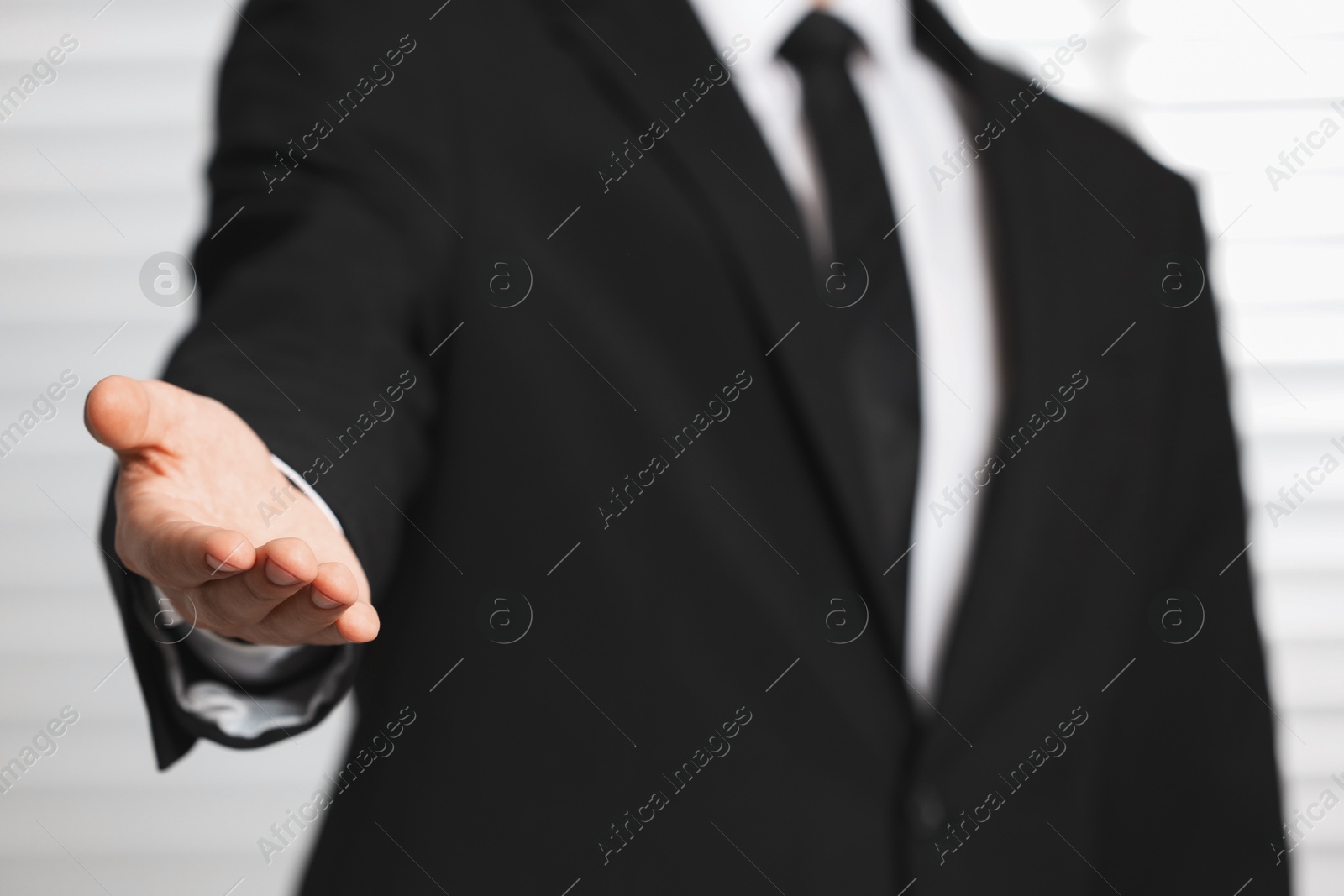 Photo of Man offering helping hand on light background, closeup