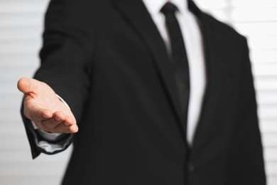 Photo of Man offering helping hand on light background, closeup