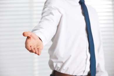 Photo of Man offering helping hand on light background, closeup