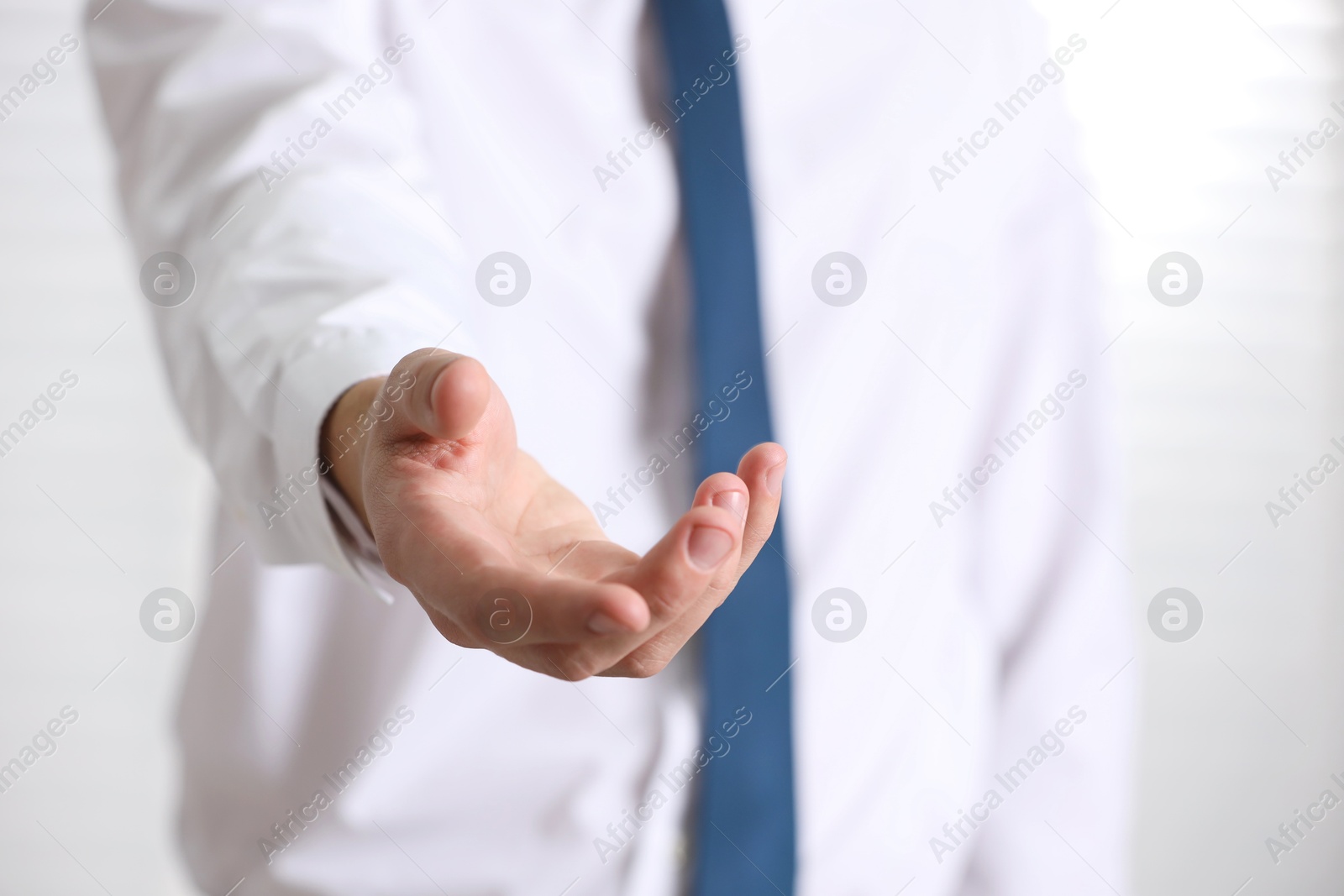 Photo of Man offering helping hand on light background, closeup