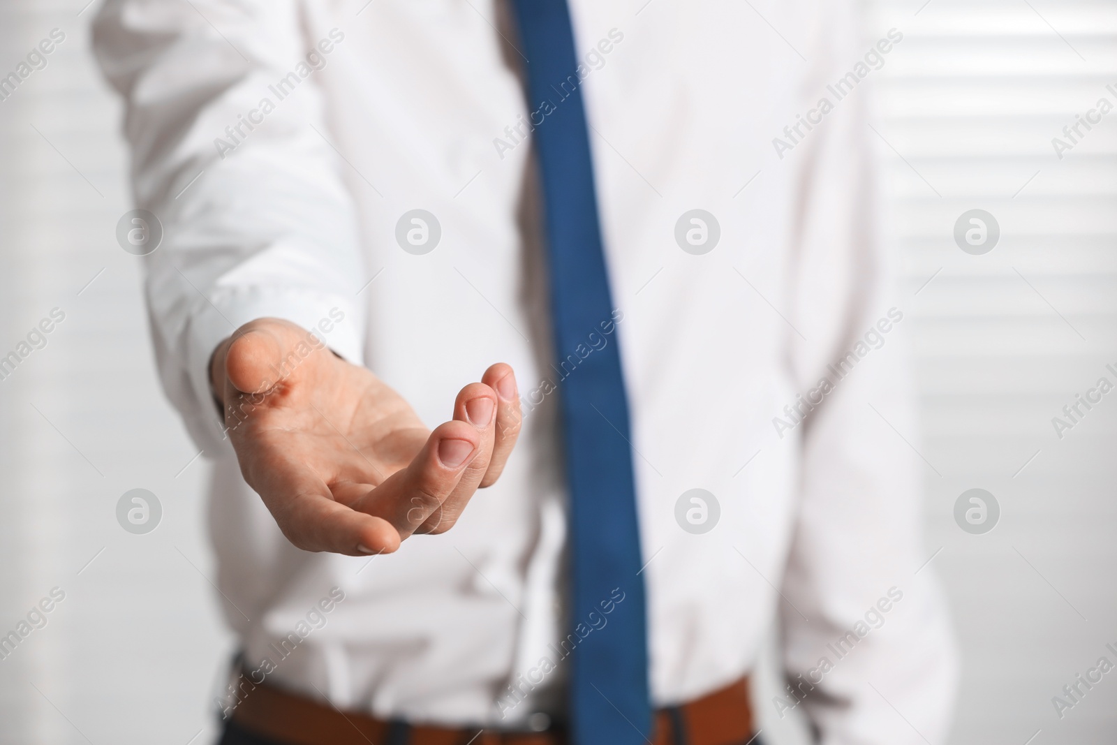 Photo of Man offering helping hand on light background, closeup