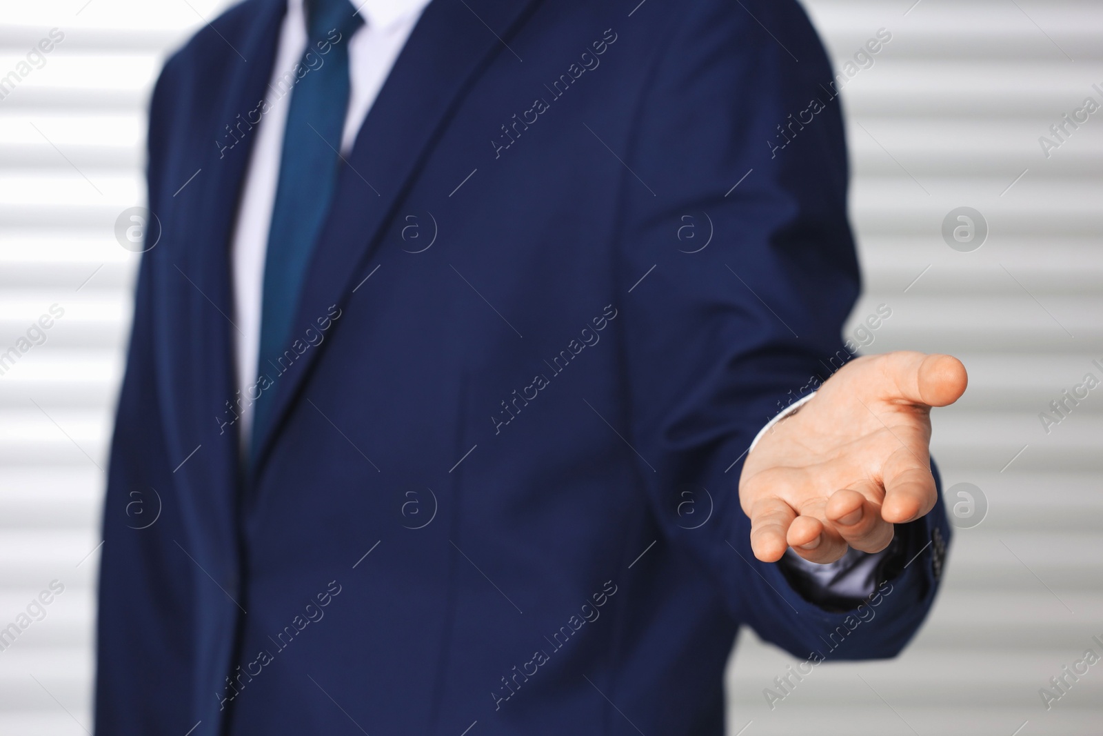 Photo of Man offering helping hand on light background, closeup