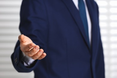 Photo of Man offering helping hand on light background, closeup