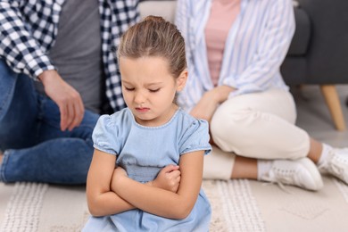 Photo of Resentful little girl and her parents at home. Family dispute