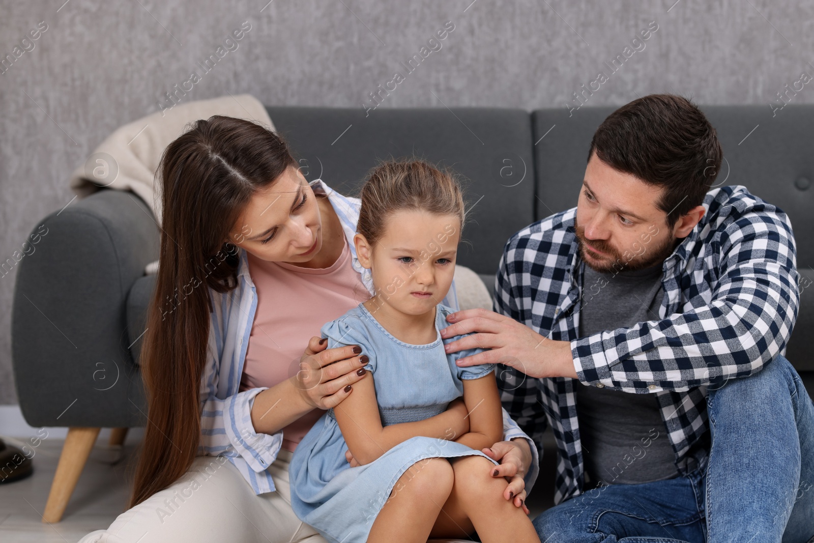 Photo of Resentful little girl and her parents at home. Family dispute