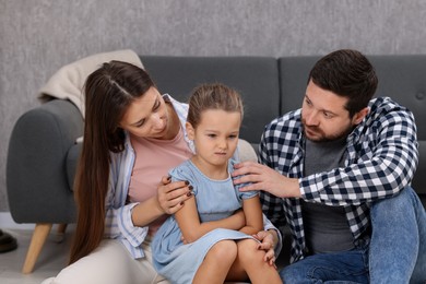 Photo of Resentful little girl and her parents at home. Family dispute