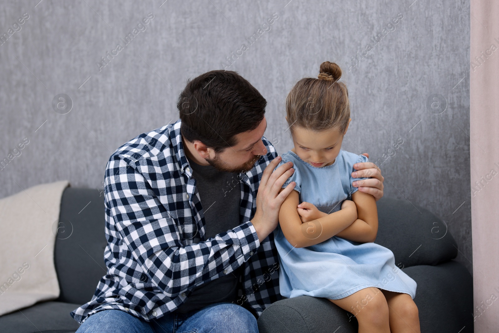 Photo of Resentful little girl and her father at home. Family dispute