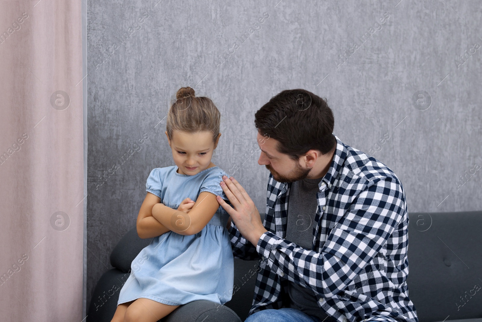 Photo of Resentful little girl and her father at home. Family dispute