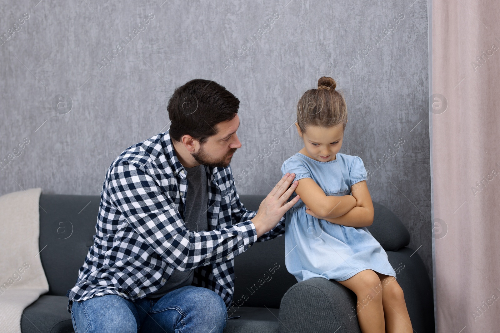 Photo of Resentful little girl and her father at home. Family dispute