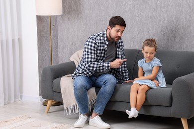 Photo of Resentful little girl and her father arguing at home, space for text