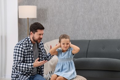 Photo of Resentful little girl and her father arguing at home, space for text