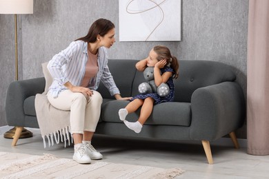 Photo of Resentful little girl and her mother arguing at home