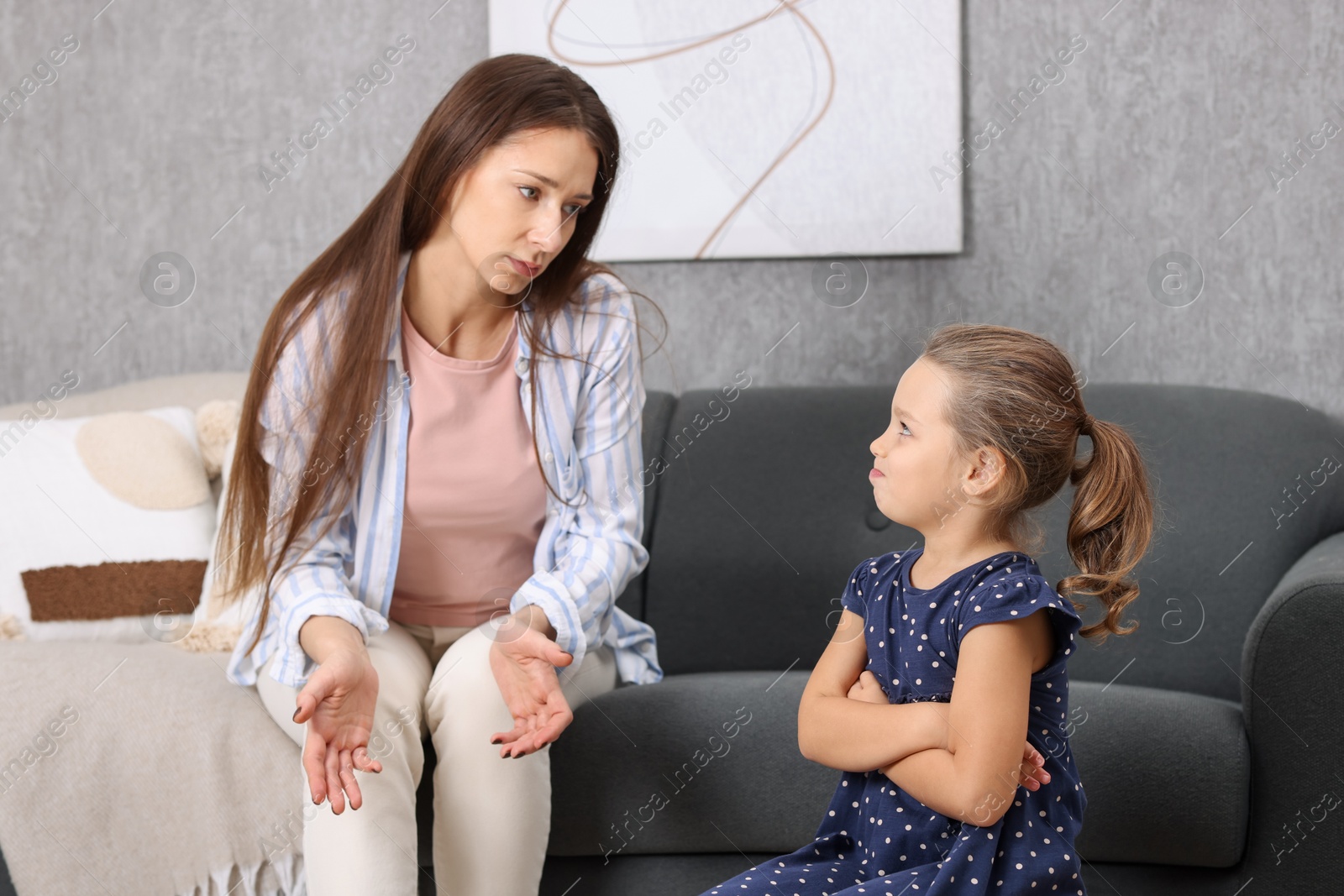 Photo of Resentful little girl and her mother arguing at home