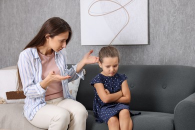 Photo of Resentful little girl and her mother arguing at home