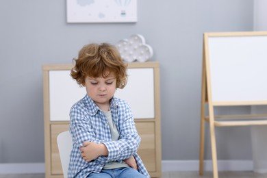 Photo of Resentful little boy indoors, space for text