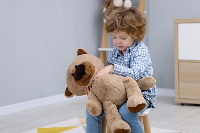 Photo of Resentful little boy with teddy bear indoors