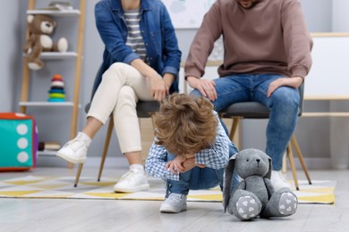 Photo of Resentful little boy and his parents arguing at home