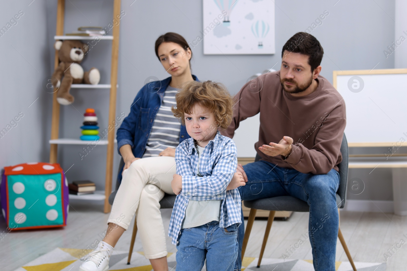 Photo of Resentful little boy and his parents arguing at home