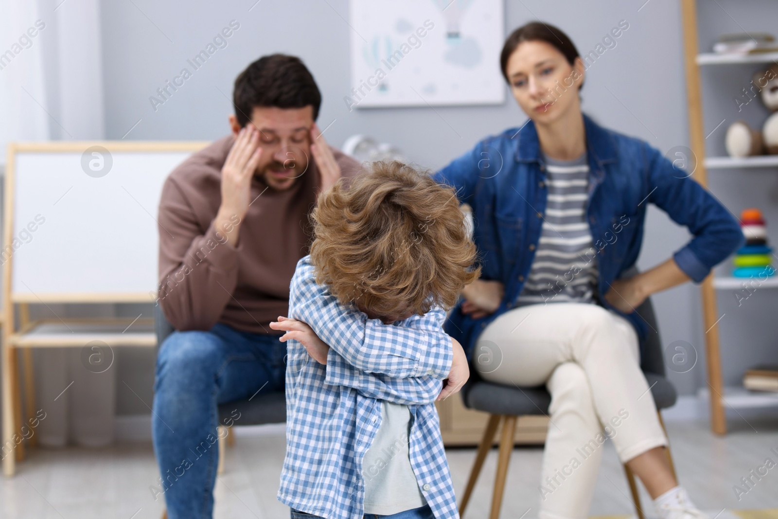 Photo of Resentful little boy and his parents arguing at home