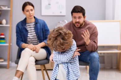 Photo of Resentful little boy and his parents arguing at home