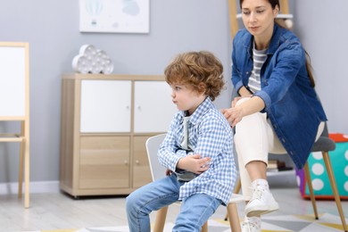 Photo of Resentful little boy and his mother arguing at home, space for text