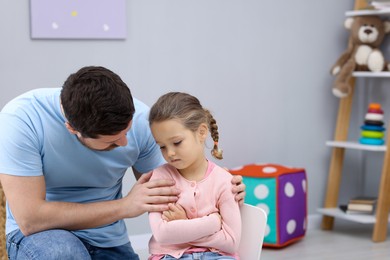 Photo of Resentful little girl and her father at home. Family dispute