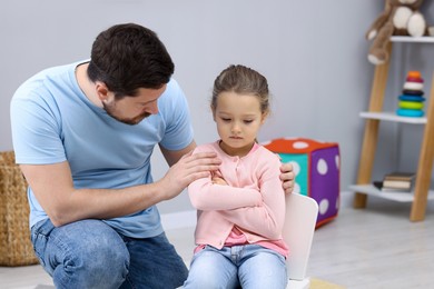 Photo of Resentful little girl and her father at home. Family dispute