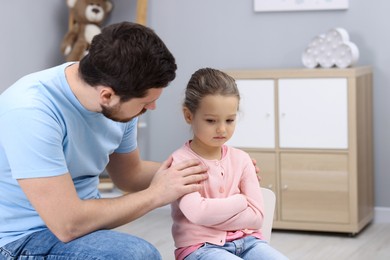 Photo of Resentful little girl and her father at home. Family dispute