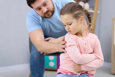 Photo of Resentful little girl and her father at home. Family dispute