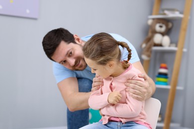 Photo of Resentful little girl and her father at home. Family dispute