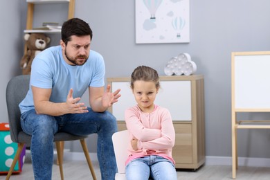 Photo of Resentful little girl and her father arguing at home