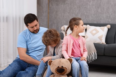 Photo of Resentful little kids and their father arguing at home