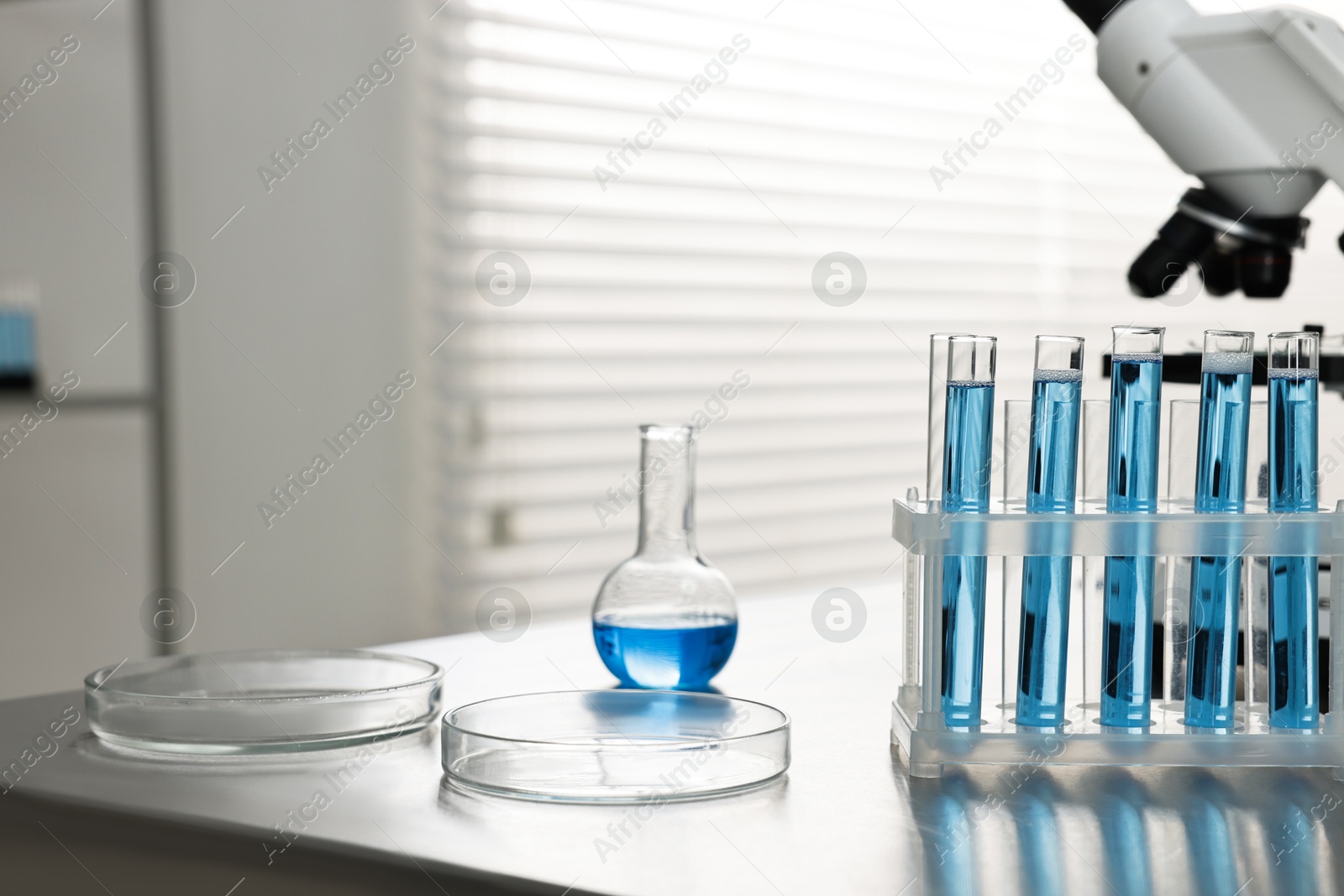 Photo of Chemical glassware and microscope on table in laboratory. Space for text