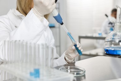 Photo of Scientist with micropipette and test tube working in laboratory, closeup