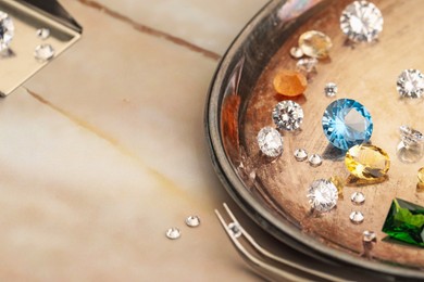 Photo of Tray with beautiful gemstones and tweezers on light table, closeup. Space for text