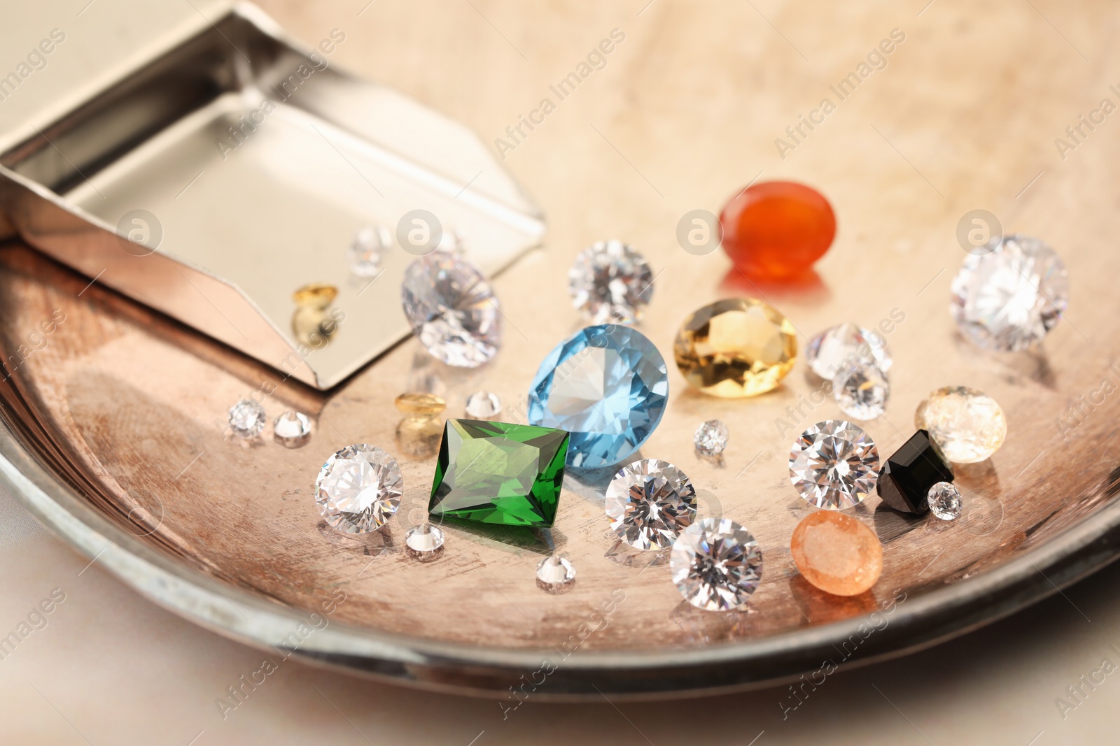 Photo of Tray with beautiful gemstones on light table, closeup