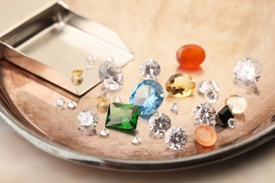 Photo of Tray with beautiful gemstones on light table, closeup