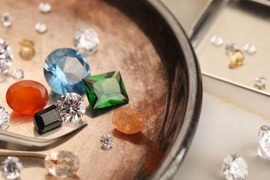 Photo of Tray with beautiful gemstones and tweezers on light table, closeup