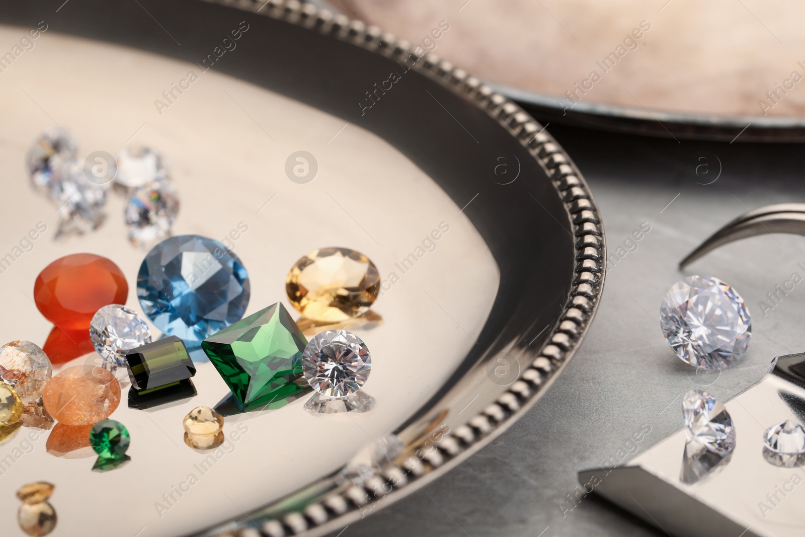 Photo of Tray with beautiful gemstones on light table, closeup