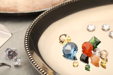 Photo of Tray with beautiful gemstones on light table, closeup