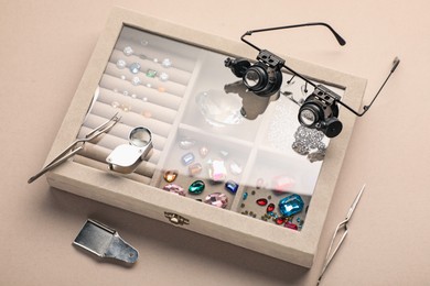 Photo of Box with beautiful gemstones and jeweler's tools on light background