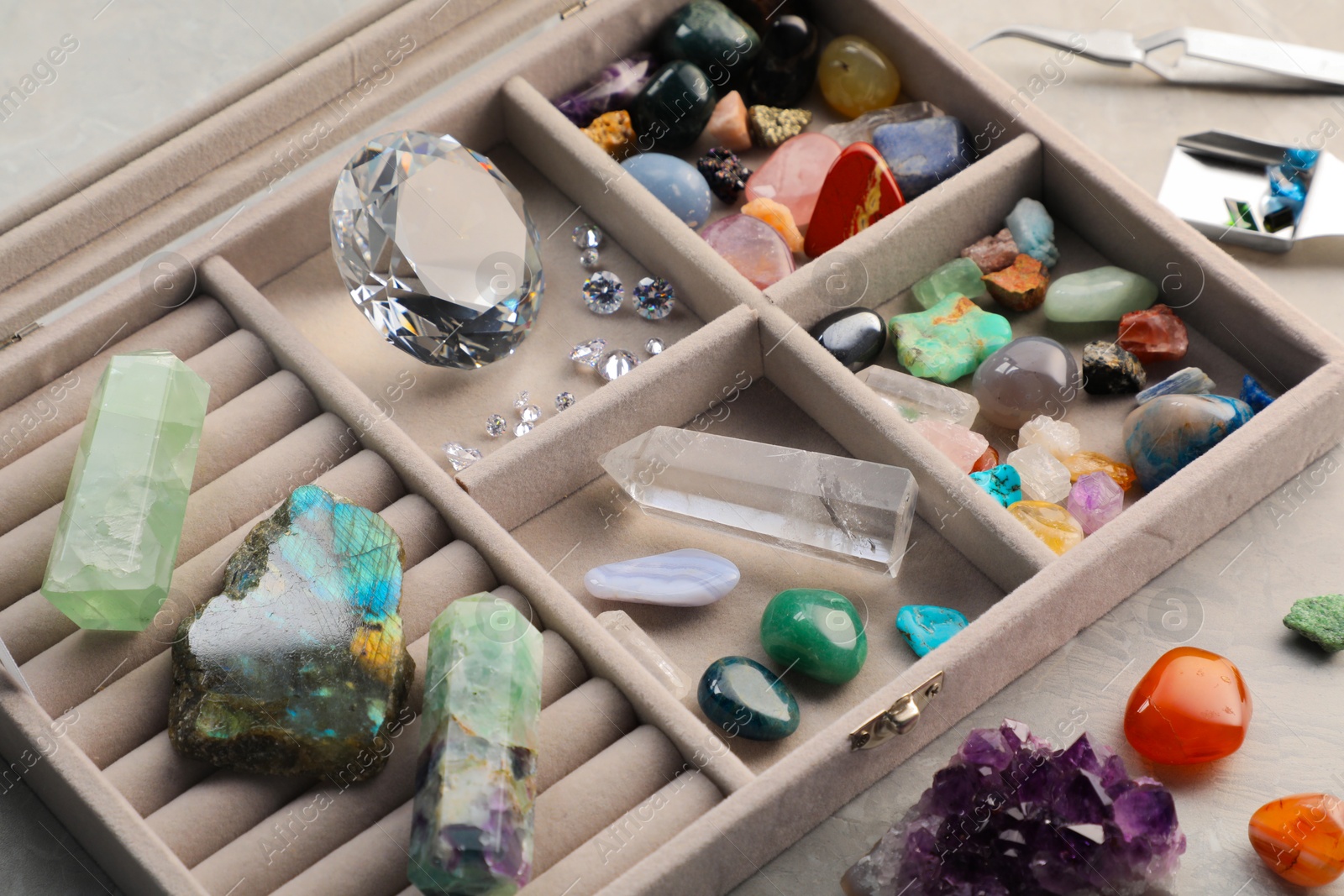 Photo of Box with beautiful gemstones on light table, closeup