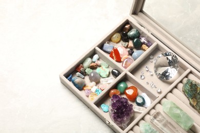 Photo of Box with beautiful gemstones on light table, closeup. Space for text