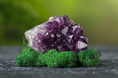 Photo of Beautiful amethyst gemstone and moss on grey textured table