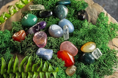 Photo of Different natural gemstones and moss on stone, closeup