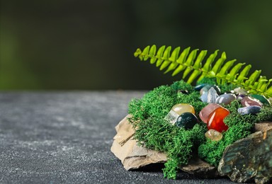 Photo of Different natural gemstones and moss on grey textured table. Space for text