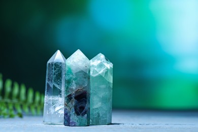 Photo of Beautiful natural gemstones on grey wooden table. Space for text